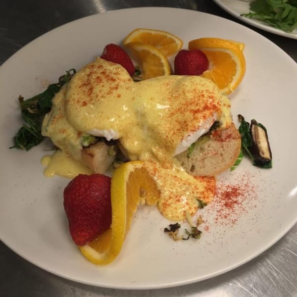 Sienna & Hope's Eggs Benedict with hollandaise sauce, paprika, strawberries, and orange slices.