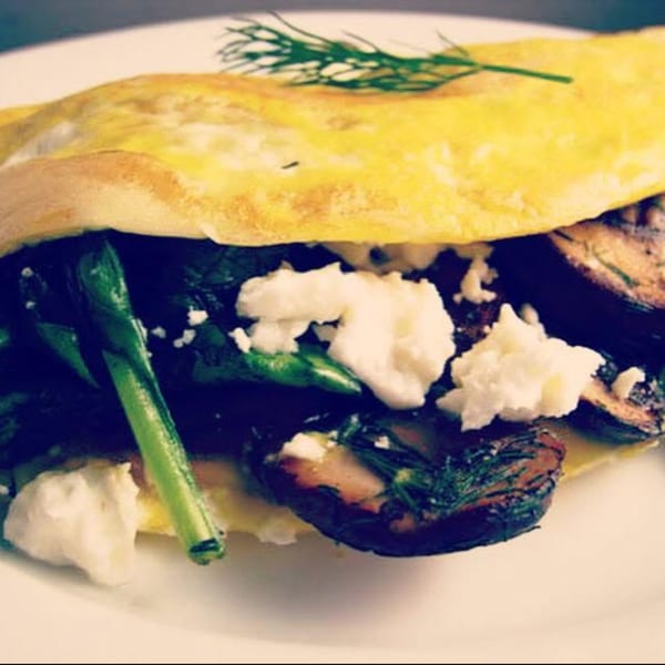 Sienna & Hope bistro's omelet with asparagus, mushrooms, feta cheese, and dill on a white plate.