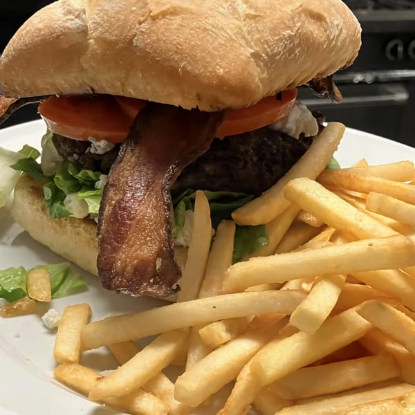 A Sienna & Hope bistro burger with bacon, lettuce, tomato, and fries on a white plate.